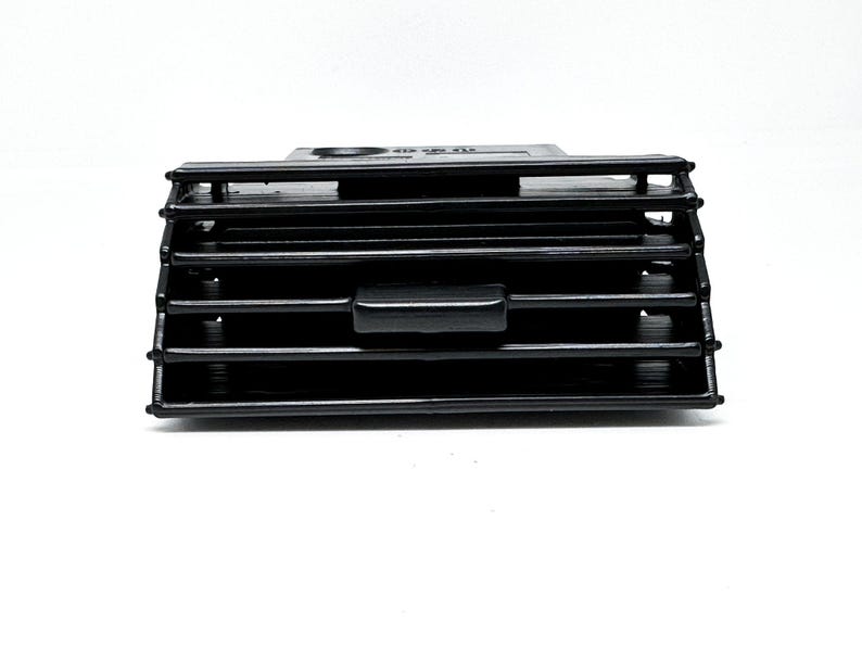 Peut inclure: A&eacute;rateur d'air de voiture en plastique noir avec des lamelles horizontales et un bouton de commande rectangulaire.