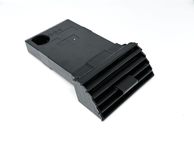 Peut inclure: A&eacute;rateur d'air de voiture en plastique noir de forme rectangulaire avec une s&eacute;rie de lamelles horizontales. L'a&eacute;rateur a une petite ouverture rectangulaire sur le dessus.