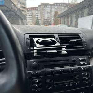 Peut inclure: Un tableau de bord de voiture noir avec un porte-gobelet noir, une radio avec des boutons et un autocollant qui dit "SUPRA FOOTWEAR COMPANY".