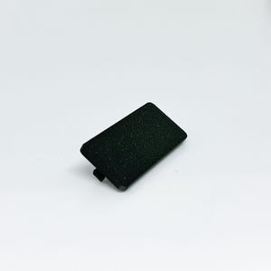 May include: A small, rectangular black plastic component with a textured surface. The component has a slightly curved edge and a small tab on one side. It is set against a plain white background.