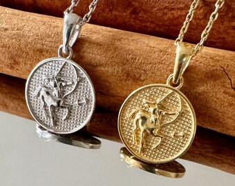 Puede incluir: Dos collares de oro y plata con un colgante del signo del zodíaco Sagitario. Los colgantes son redondos y presentan un diseño detallado de un centauro sosteniendo un arco y una flecha.