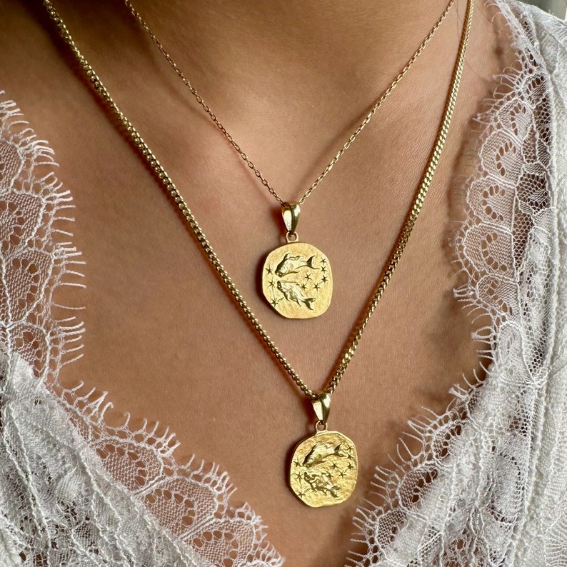 Pisces pendant in the shape of a coin hanging around the neck. Golden color.