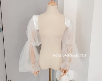 May include: White tulle sleeves with satin trim. The sleeves are gathered at the wrist and have a loose, flowing fit.