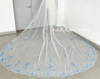 May include: A long white bridal veil with a scalloped edge and blue floral embroidery. The veil is made of soft tulle and is perfect for a wedding.