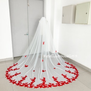 May include: A white bridal veil with a long, flowing design. The veil is decorated with red floral lace around the edges and scattered throughout the veil. The text "FashionS GoodieUS" is visible in the lower center of the image.