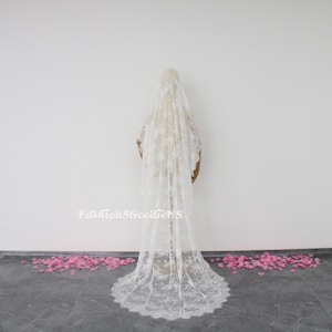 May include: A white lace wedding veil with a scalloped edge. The veil is long and flowing, and it is shown on a white background.