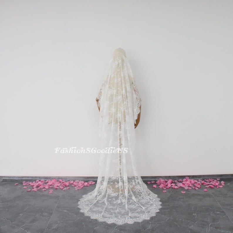May include: A white lace wedding veil with a scalloped edge. The veil is long and flowing, and it is shown on a white background.