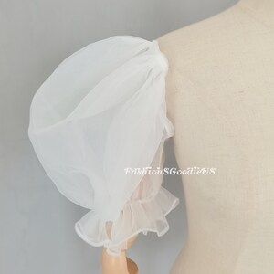 May include: White sheer puff sleeve with a ruffled cuff. The sleeve is made of a lightweight, airy fabric and is attached to a mannequin. The text "FashionSGoodieUS" is visible on the image.