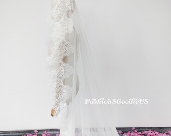 May include: A white bridal veil with intricate lace detailing along the edge. The veil is long and flowing, with a delicate, sheer appearance. The text "FashionSGoodieUS" is visible on the veil.