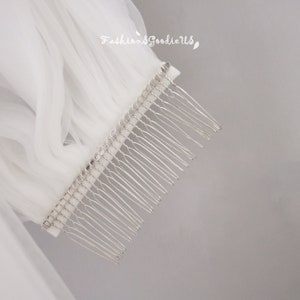 May include: A white tulle veil with a silver comb. The comb has a row of small rhinestones.