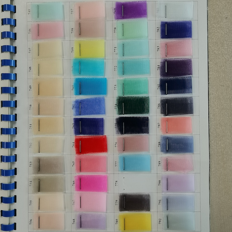 May include: A color chart of 40 different shades of tulle fabric. The chart is organized in rows and columns, with each square containing a different color of tulle. The colors range from light pink to dark blue, with many shades of green, yellow, and red in between.