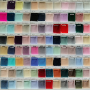 May include: A colour chart of 100 different shades of tulle fabric. The fabric is arranged in rows and columns, with each square labelled with a number. The colours range from light to dark, and from cool to warm.