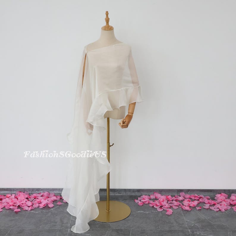 Pu&ograve; includere: Scialle di chiffon bianco trasparente con bordo arricciato. Lo scialle &egrave; drappeggiato su un manichino e ha una lunga coda fluida.