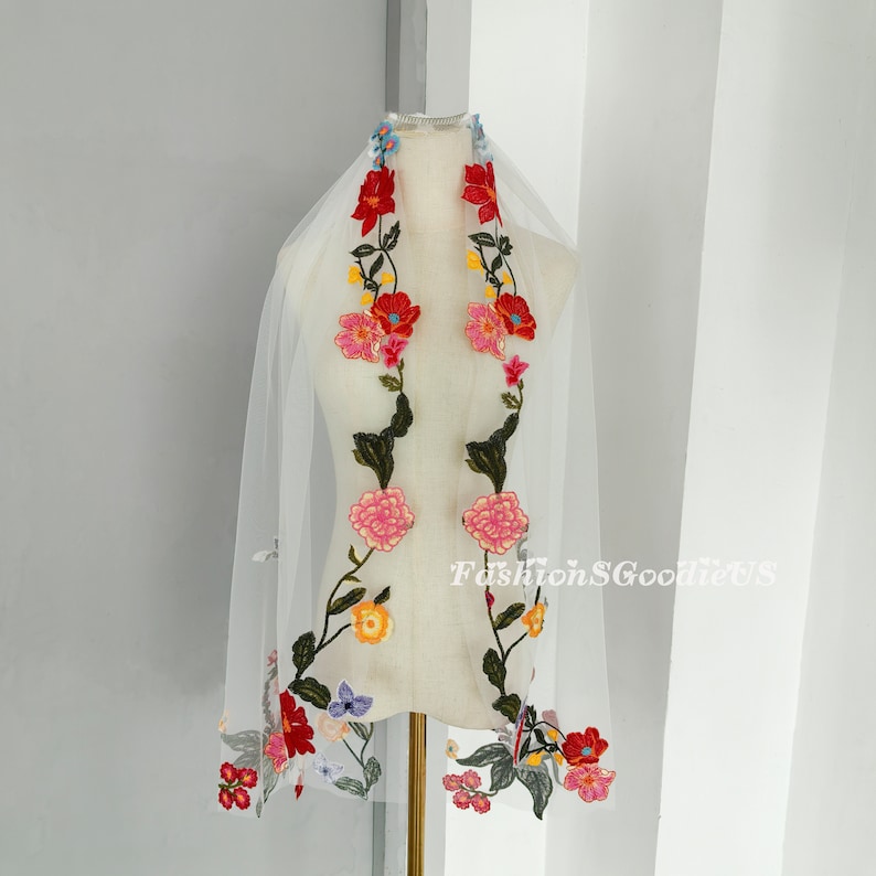 May include: White bridal veil with colourful floral embroidery. The embroidery features red, pink, yellow, blue and green flowers.