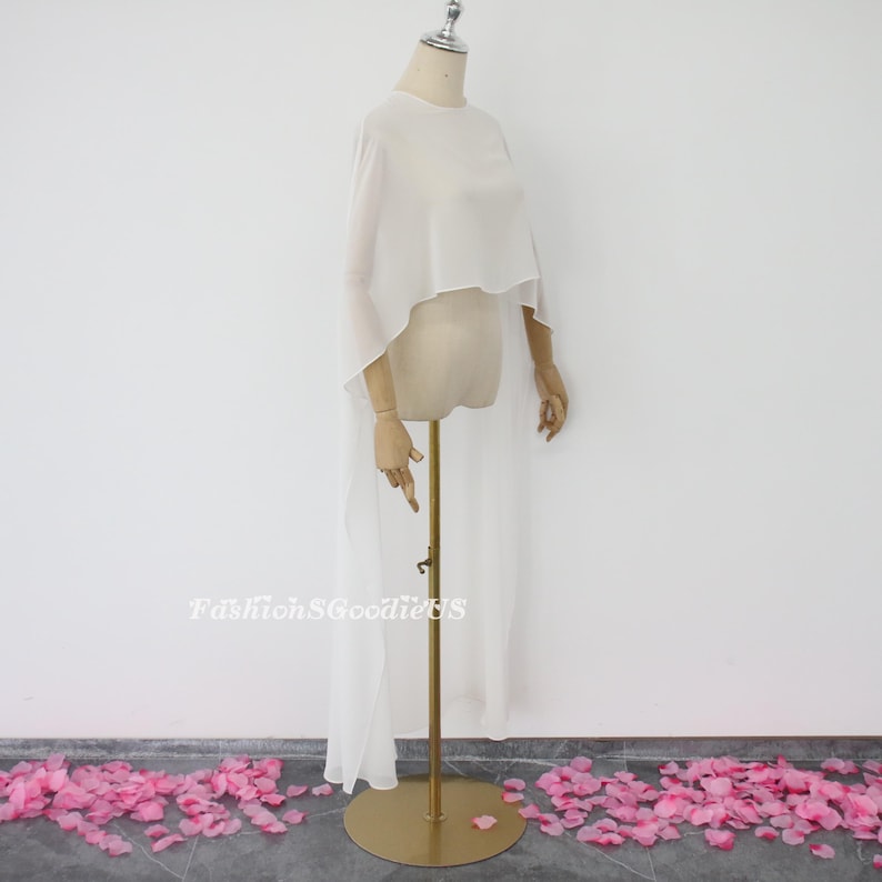 May include: White sheer chiffon cape with a high neckline and a long train. The cape is draped over a mannequin and is displayed against a white background.