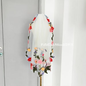 May include: White bridal veil with colourful floral embroidery. The embroidery features red, pink, yellow, blue and green flowers.