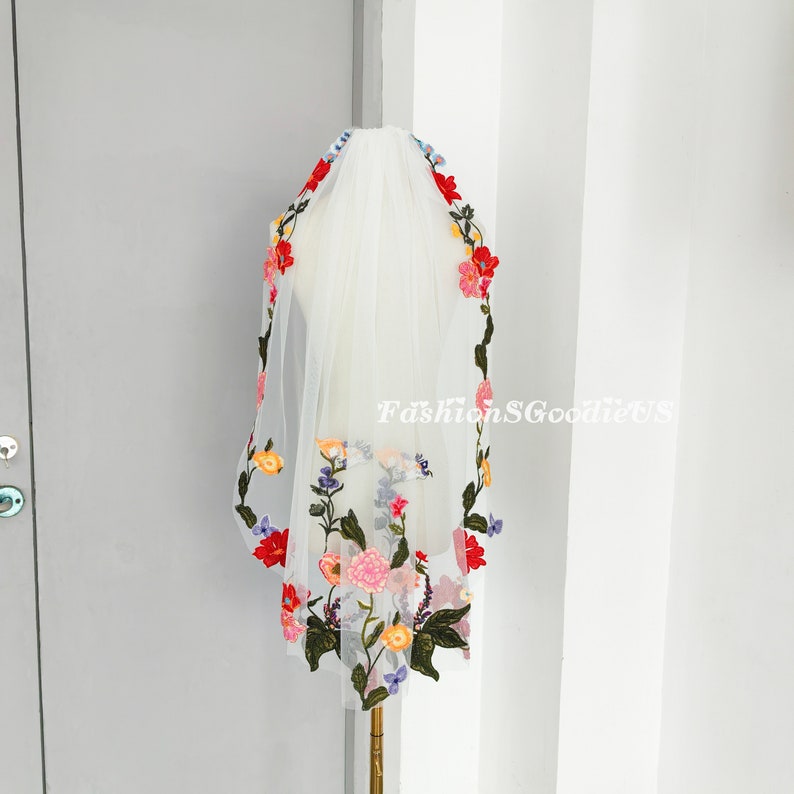May include: White bridal veil with colourful floral embroidery. The embroidery features red, pink, yellow, blue and green flowers.