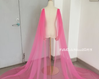 May include: A pink tulle cape with a long train. The cape is draped over a white mannequin.