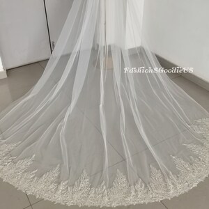May include: A white bridal veil with a beaded lace trim. The veil is made of soft tulle and is very long.