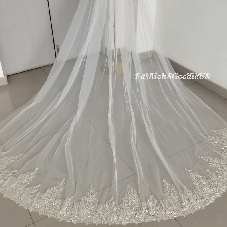 May include: A white bridal veil with a beaded lace trim. The veil is made of soft tulle and is very long.