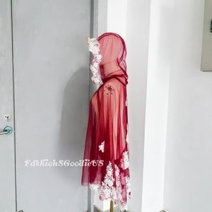 Pode incluir: Uma capa de tule bord&ocirc; com detalhes em renda branca e capuz. A capa &eacute; feita de um tecido leve e tem uma silhueta fluida.