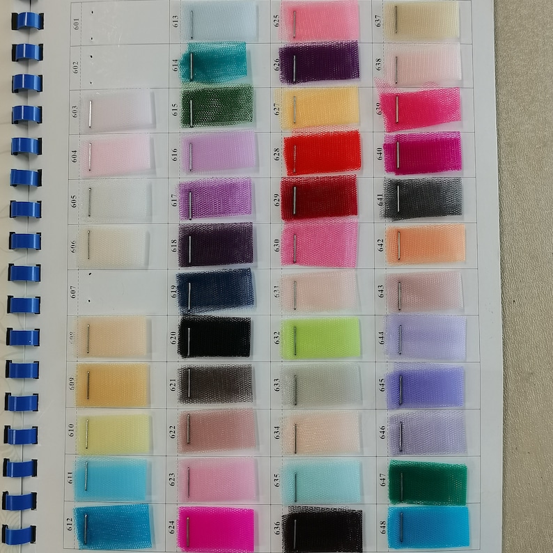 May include: A color chart of 60 different shades of tulle fabric. The chart is numbered from 601 to 648. The colors range from white, black, and gray to bright colors like pink, blue, green, and yellow.