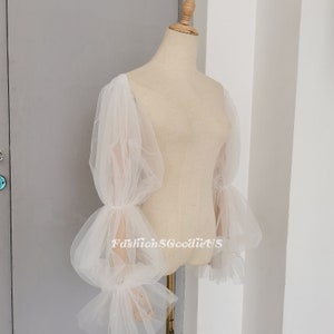 May include: White tulle sleeves with a gathered, puffed design. The sleeves are long and have a delicate, flowing look.