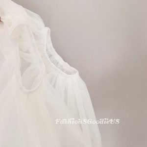 Pu&ograve; includere: Tessuto bianco trasparente con scollo arricciato. Il tessuto &egrave; morbido e delicato, e lo scollo &egrave; arricciato per creare un look ampio e fluido.