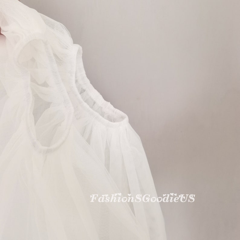 Pu&ograve; includere: Tessuto bianco trasparente con scollo arricciato. Il tessuto &egrave; morbido e delicato, e lo scollo &egrave; arricciato per creare un look ampio e fluido.
