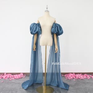 May include: A pair of long, flowing blue sleeves with large, puffed shoulders. The sleeves are made of a sheer fabric and are attached to a mannequin.