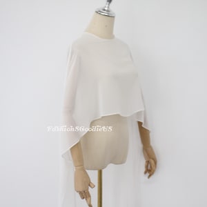 May include: White sheer chiffon cape with a rounded neckline and long flowing sleeves. The cape is draped over a dress form.