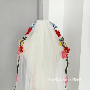 May include: White bridal veil with colourful floral embroidery. The embroidery features red, pink, yellow, blue and green flowers.