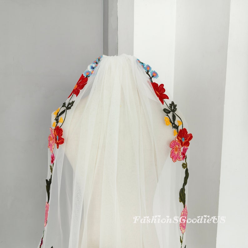 May include: White bridal veil with colourful floral embroidery. The embroidery features red, pink, yellow, blue and green flowers.