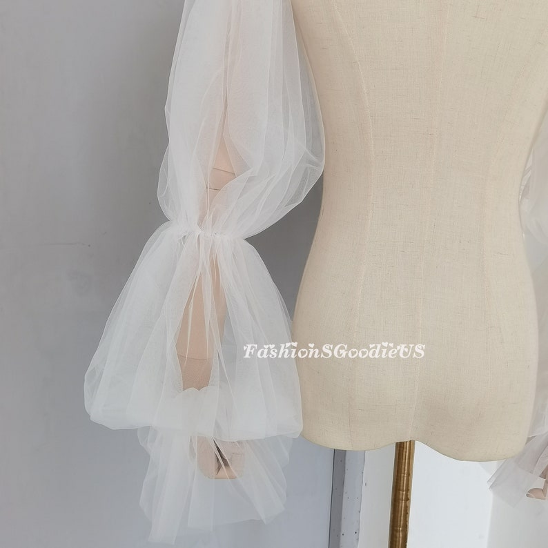 May include: White tulle sleeves with a gathered and ruffled design. The sleeves are sheer and delicate, and they would be perfect for a wedding or other special occasion.