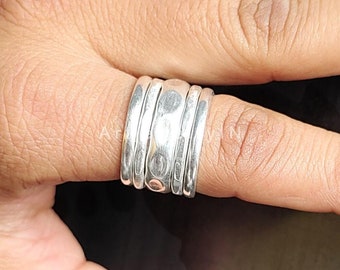 Könnte beinhalten: Ein silberner Ring mit gehämmerter Textur. Der Ring besteht aus mehreren übereinander gestapelten Bändern.