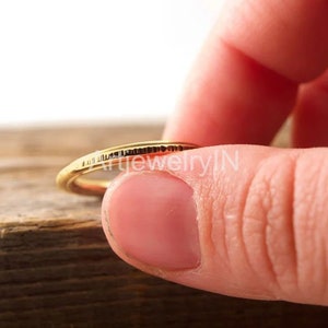 Puede incluir: Un anillo de banda de oro delgado con una superficie texturizada.