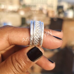 Puede incluir: Un anillo de plata con un diseño texturizado. El anillo está formado por cuatro bandas que están apiladas una encima de la otra.