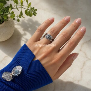 May include: A silver ring featuring a multi-band design with textured, beaded, and smooth metallic strands layered together. The ring is worn on a finger, and the text ArtjewelryIN is visible in the center of the image near the ring.
