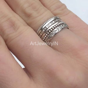 Peut inclure: Un ensemble de quatre bagues empilables en argent. Les bagues sont toutes de styles différents, l'une avec un motif floral, l'autre avec un motif perlé et deux avec des bandes texturées.