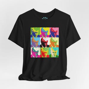 Może przedstawiać: Czarny T-shirt z kolorowym wzorem w stylu pop art przedstawiającym twarz mężczyzny powtórzoną dziewięć razy.
