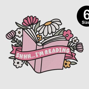 May include: Pink and white embroidery design of a book with flowers and the text "Shhh... I'm reading".