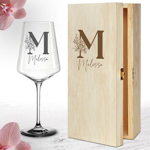 Könnte beinhalten: Ein klares Weinglas mit einem floralen Design und dem Buchstaben "M" sowie dem Namen "Melissa" eingraviert. Das Glas befindet sich in einer Holzkiste mit dem gleichen Design.