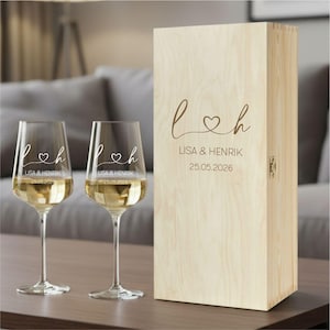 May include: Two clear glass wine glasses and a tall rectangular light-colored wooden box. Each glass and the box feature the engraved text L, a heart symbol, h, the names LISA & HENRIK, and the date 25.05.2026 in a matching script font.
