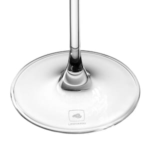 May include: A clear glass stemware base with a circular footprint and a slender vertical stem rising from the center. The base features a small square logo with a stylized bird icon and the text LEONARDO etched into the surface of the glass.