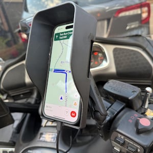 May include: A black motorcycle phone mount with a sunshade, holding a smartphone displaying a map app with the text "Two Run Creek Trail NW".