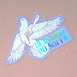 以下が含まれることがあります： フォークで刺されたハトが描かれたステッカーで、虹色の文字で「DEAD DOVE DO NOT EAT」と書かれています。ハトは白い羽毛が細かく描かれており、ステッカーは薄紫色の縁取りです。
