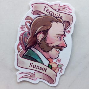 Peut inclure: Un autocollant représentant un homme de dessin animé avec une moustache et une barbe. L'homme porte une veste verte et une chemise blanche. L'autocollant a une bannière qui dit "Tequila Sunset" en lettres roses et blanches.