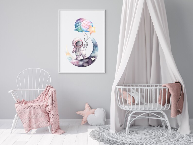 May include: Watercolor print of an astronaut on a crescent moon holding planet and star balloons. The artwork features a soft color palette of blues, purples, and pinks, perfect for a nursery or children's room. The print is framed in a white frame.