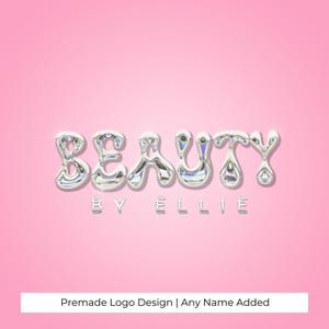 May include: A silver metallic logo design with the word "BEAUTY" in a bubbly font. The text "BY ELLIE" is below the word "BEAUTY". The logo is on a pink background.