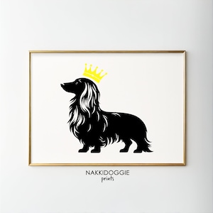 May include: Black silhouette of a long-haired dachshund wearing a yellow crown. The image is on a white background with a gold frame. The text "NAKKIDOGGIE prints" is at the bottom of the image.